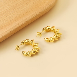 Détail de boucles d'oreilles créoles torsadées dorées avec finition métallique brillante