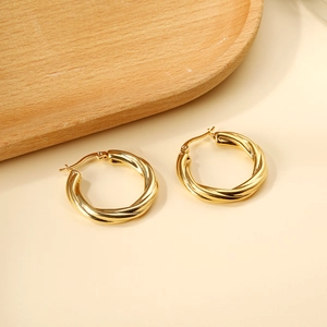 Vue macro de boucles d'oreilles créoles dorées torsadées en C avec finition texturée