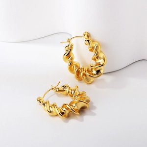 Détail macro de boucles d'oreilles créoles dorées torsadées avec un motif en spirale