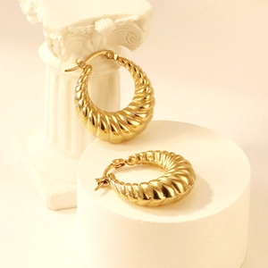 Détail de boucles d'oreilles créoles dorées en C avec texture spirale et fermoir levier