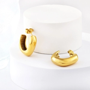 Gros plan de boucles d'oreilles dorées en C torsadées avec texture rayée