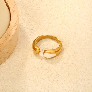 Primo piano di anello dorato irregolare con goccia di smalto bianco e design a curve fluide