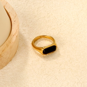 Retro gold stainless steel wide ring with rectangular black agate stone on beige texture