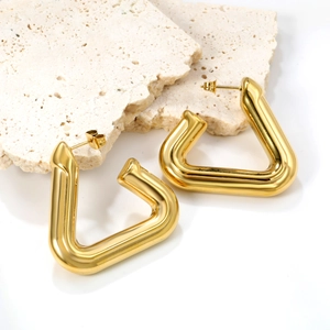 Chic hollow triangular gold stud earrings with polished mirror finish on travertine