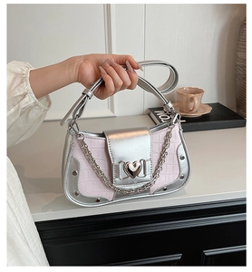 Detail of silver heart metal clasp and pink crocodile pattern on a chic crossbody bag