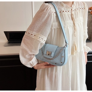 Detail of light blue croc-embossed shoulder bag featuring heart buckle and silver chain