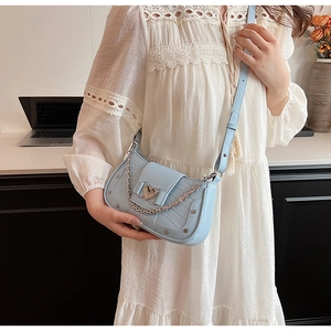 Detail of light blue crocodile pattern bag with heart-shaped metal lock and silver chain
