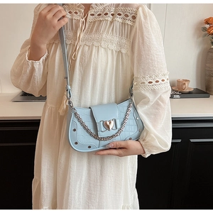 Detail of light blue crocodile texture bag with heart metal buckle and silver chain
