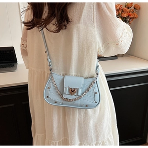 Detailed view of light blue croc-embossed bag with gold heart clasp and chain strap