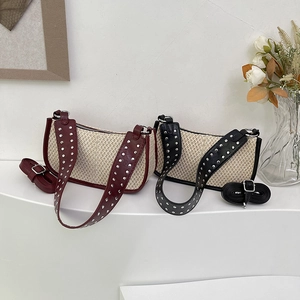 Straw hobo bags with rivet straps in burgundy and black, shown on a white pedestal