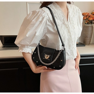 Detail of black faux crocodile skin bag with silver heart lock and chunky chain