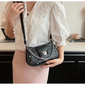 Detail of black faux leather baguette bag with silver heart buckle and chain strap