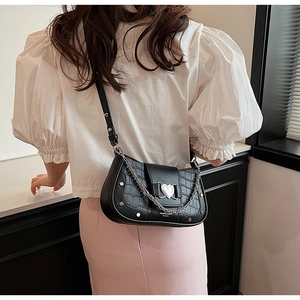 Detail of black faux leather underarm bag featuring crocodile pattern and silver heart clasp