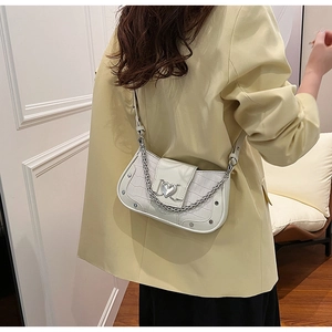 Detail view of white croc-embossed underarm bag with silver heart charm and metal chain
