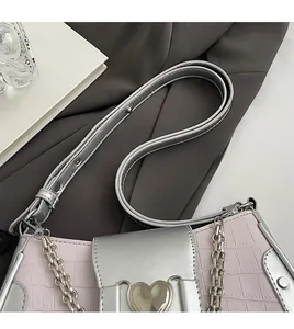 Detail of pink croc-embossed leather underarm bag with silver chain and heart buckle