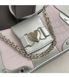 Detailed view of pink croc-embossed leather underarm bag with silver heart buckle and chain