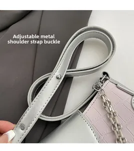 Detail of adjustable metal buckle and pink faux croc leather strap on chain bag