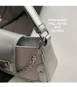 Detail of silver heart buckle and detachable chain link on pink faux leather bag