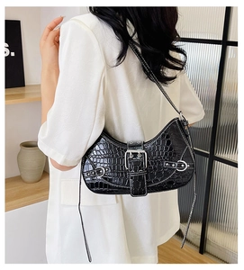 Gros plan du sac porté épaule noir à motif crocodile avec boucle argentée sur modèle