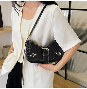 Détail d'un sac hobo noir à motif crocodile avec boucle argentée porté par un mannequin