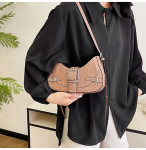 Détail d'un sac demi-lune marron à motif crocodile avec une boucle en métal argenté