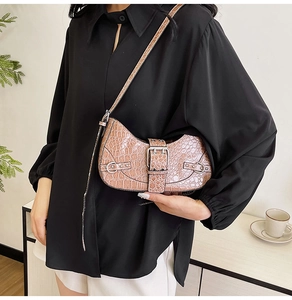 Sac demi-lune marron effet crocodile avec boucle en métal porté par un mannequin élégant
