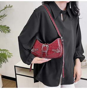 Détails de la texture crocodile et boucle argentée sur le sac à bandoulière rouge foncé