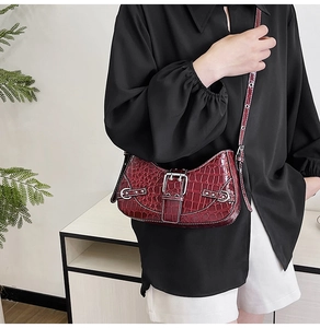 Gros plan du sac bandoulière rouge motif crocodile avec texture brillante et boucle métal