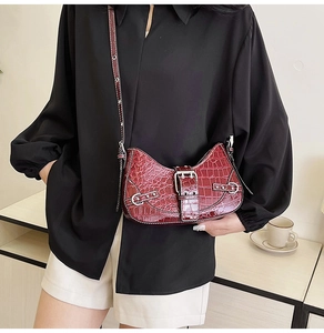 Détail du sac à bandoulière bordeaux à motif crocodile avec boucle et design incurvé