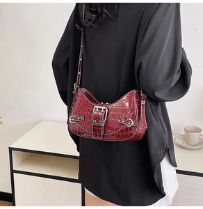 Détail du sac à bandoulière bordeaux motif crocodile avec boucles argentées