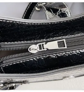 Détail du sac à main noir motif crocodile avec fermeture éclair en métal argenté poli