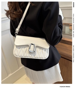 Close-up of a white pleated shoulder bag with a silver buckle worn by a model