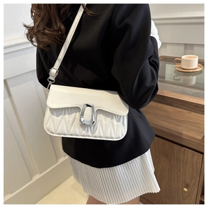 Detail of white quilted crossbody bag featuring a silver metal clasp and wavy stitching