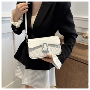 Detail of white pleated small square bag with silver buckle worn by a model in black blazer