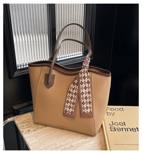 Detail of lychee textured leather tote bag with elegant checkered silk scarf handle