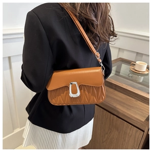 Detailed back view of a brown pleated crossbody bag with silver buckle on a model