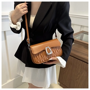 Detail view of brown matelassé pleated handbag with a large silver U-shaped buckle decoration