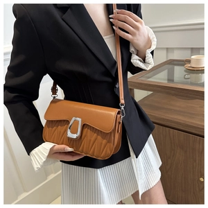 Close-up of brown pleated crossbody bag with silver U-shaped metal buckle on model
