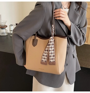 Detail view of khaki pebbled leather tote bag with brown trim and silk scarf accent