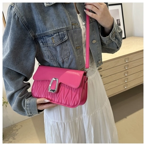 Detail of bright pink pleated crossbody bag with silver U-shaped metal buckle on a model