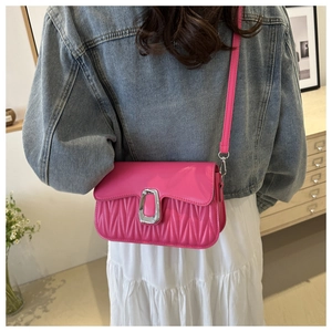 Detail of fuchsia quilted crossbody bag with silver buckle worn by model