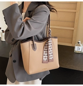 Detail of beige leather tote bag with brown trim and decorative checkered silk scarf