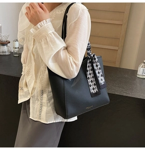 Detail of black lychee leather tote bag with a checkered silk scarf on the handle