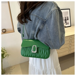 Detail of green pleated crossbody bag with large silver U-shaped buckle on a model