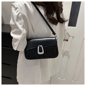 Detail of black quilted crossbody bag featuring V-shaped pleats and silver metal buckle