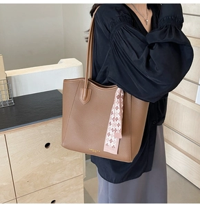 Detail of brown lychee leather tote bag with silk scarf and gold lettering logo