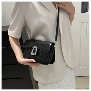 Detail of black crossbody bag featuring vertical pleats and silver metallic buckle closure