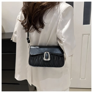 Detail of black pleated crossbody bag with silver U-shaped metal buckle and smooth flap