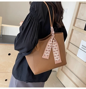 Detail of brown leather tote bag with lychee texture and decorative silk scarf