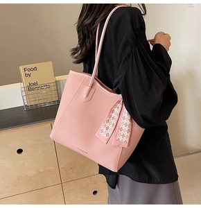 Detail of pink lychee leather tote bag with elegant checkered silk scarf on handle